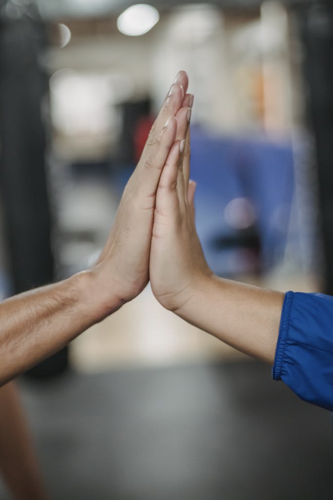 Crop faceless people clapping hands in room